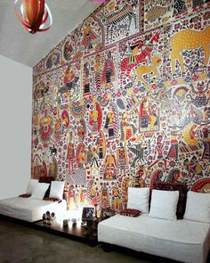 a living room filled with white couches next to a wall covered in colorful paintings