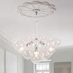 a chandelier hanging from the ceiling in a room with white walls and windows