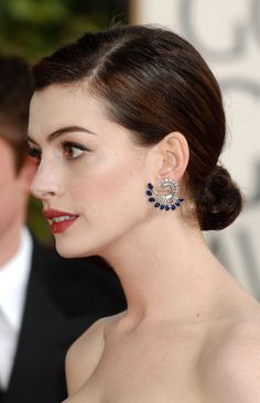 a woman in a strapless dress with blue earrings on her left ear, looking off to the side