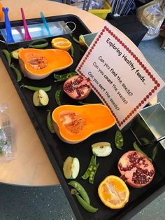 a tray filled with cut up fruit on top of a table next to a sign