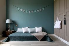 a bedroom painted in teal and white with bunting flags hanging from the ceiling