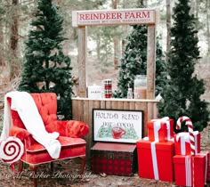 a red chair sitting in the middle of a forest filled with christmas trees and presents