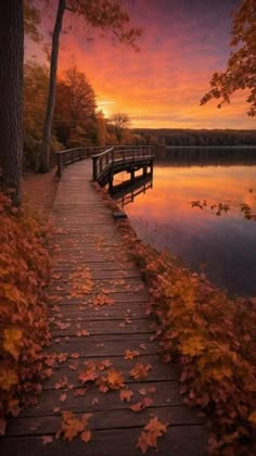 a wooden walkway leading to a lake at sunset