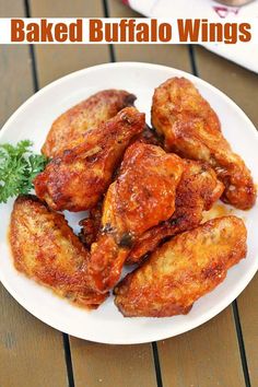 baked buffalo wings on a white plate with garnish and parsley in the background