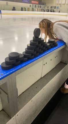 a woman leaning over to look at an ice rink