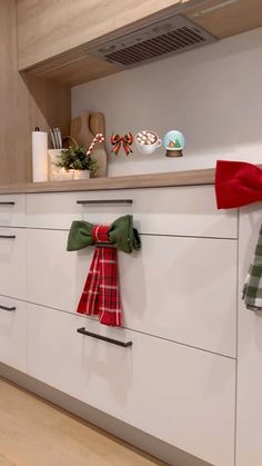 the kitchen is decorated for christmas with red, green and white bow ties on the cabinets