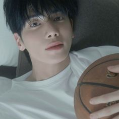 a young man holding a basketball in his right hand and looking at the camera while sitting on a couch