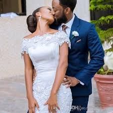 a bride and groom kissing in front of a building with potted plants behind them