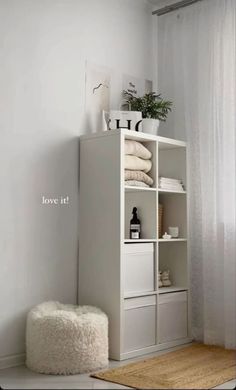 a white shelf with towels and other items on it in a small room next to a window