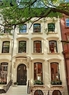 a large white building with many windows and steps leading up to the front door,