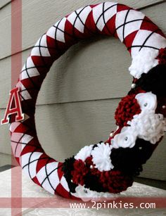 a red and white wreath with the letter a on it sitting in front of a house