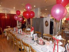 a table set up for a party with pink and red balloons