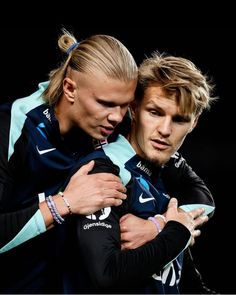 two young men hugging each other in front of a black background