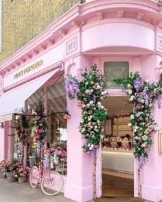 a pink store front with flowers on the outside