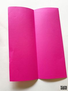 an open pink paper book sitting on top of a table