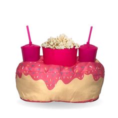 a pink and gold donut shaped table with two cups filled with popcorn on top