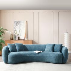 a blue couch sitting on top of a white floor next to a wooden table and plant