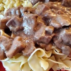 a red plate topped with pasta and meat covered in gravy