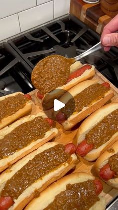 several hot dogs on buns with mustard and ketchup sitting on a cutting board