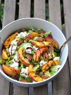 a white bowl filled with salad sitting on top of a wooden table