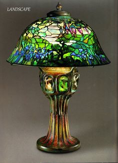 a table lamp with a green and blue shade on it's top, sitting on a gray surface