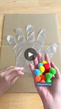 someone is making a hand made out of plastic wrappers and gummy balls with their hands