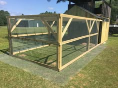 a large chicken coop in the middle of a field with grass and trees around it