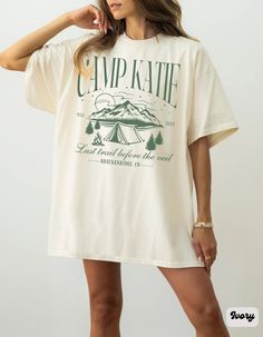 a woman wearing a white camp kate t - shirt dress with trees and mountains on it