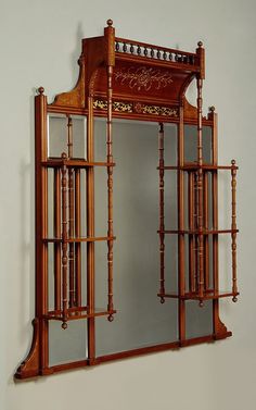 an ornate wooden mirror hanging on the wall next to a shelf with shelves below it