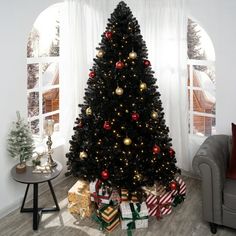 a black christmas tree with red and gold ornaments is in the corner of a living room