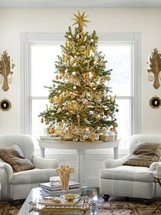 a living room with a christmas tree in the corner and two white chairs around it