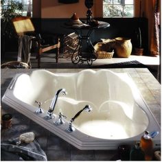 a large white bath tub sitting on top of a tiled floor next to a table