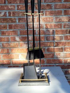 a broom and dustpan on a table in front of a brick wall with a metal holder