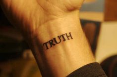 a person with a tattoo on their wrist that says truth written in black ink,