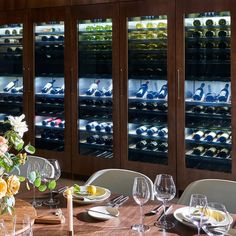 a dining room table is set with wine bottles and glasses in front of the wall