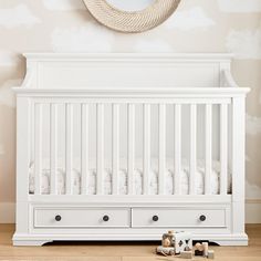 a white crib with two drawers and a mirror on the wall next to it