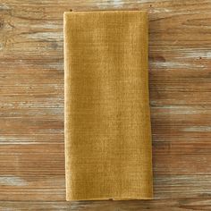 a yellow linen napkin sitting on top of a wooden table