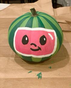 a watermelon painted like a face sitting on top of brown paper