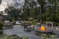 a fire pit surrounded by chairs and tables in the middle of a yard with an outdoor fireplace