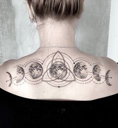 the back of a woman's shoulder with phases of planets and stars on it