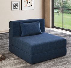 a blue chaise lounge chair sitting on top of a rug in front of a window