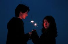 two people standing next to each other holding sparklers