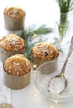 four muffins with powdered sugar in them and a spoon on the side