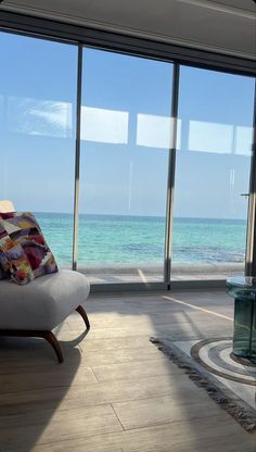 a living room filled with furniture and large windows overlooking the ocean on a sunny day