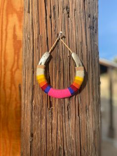 a wooden pole with a colorful bracelet hanging from it's side on top of it