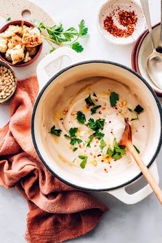 a pot filled with white sauce and garnished with parsley next to other dishes