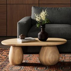 a living room with a couch, coffee table and vase on the floor in front of it