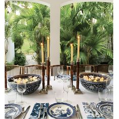 the table is set with blue and white plates, silverware, candles and place settings