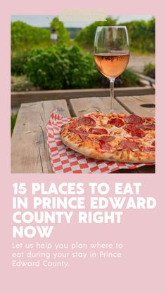 a pizza sitting on top of a wooden table next to a glass of wine