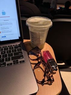 an open laptop computer sitting on top of a wooden table next to a cup of coffee